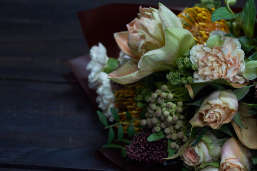En bukett med olika blommor inklusive stora rosor och frodigt grönt.